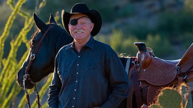 Bill Owen standing with horse by cactus