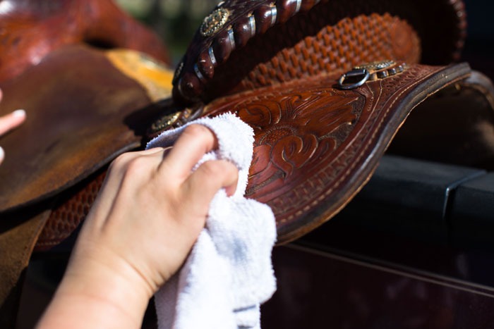 person cleaning fender on saddle