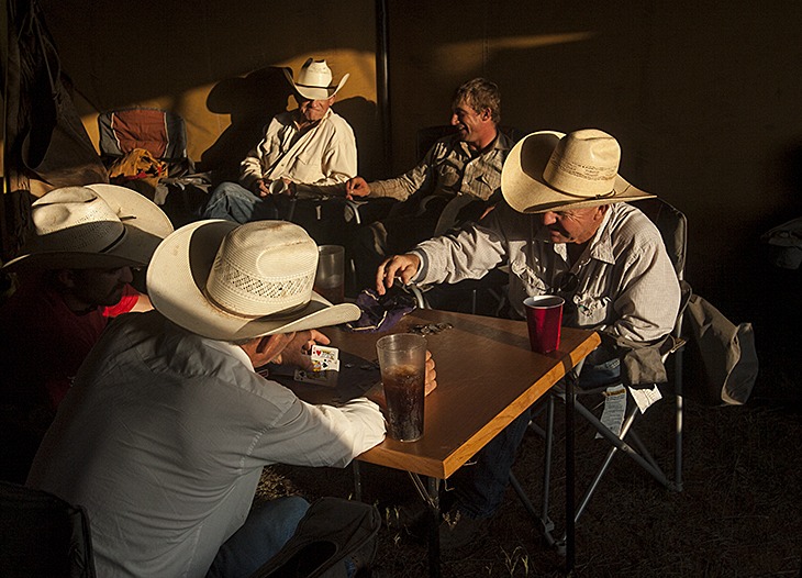 Wagon boss Reggie Hatfield (right) plays poker with his men under the wagon fly.