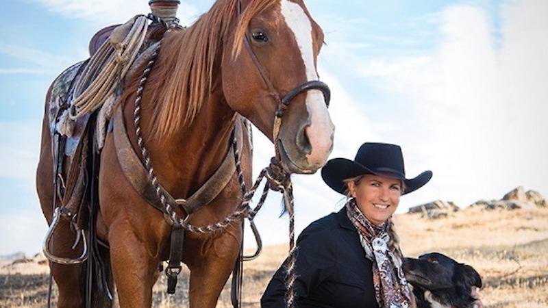 Diana Bohna sitting with dog next to horse