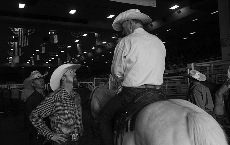 Cowboys visiting about a horse.