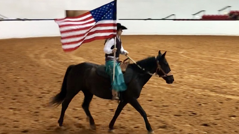 Shelby Crider riding mustang Pearl carrying American flag