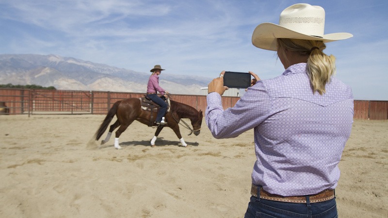 Cowgirl taking video of girl on horse cell phone