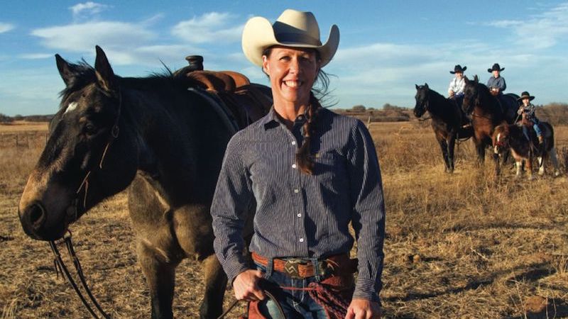 Lori Campbell standing by horse with family in background