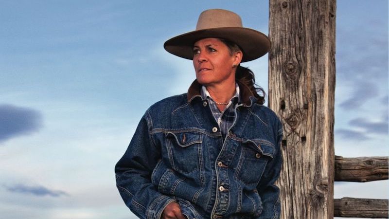 Lisa Robinson leaning back against a fence post