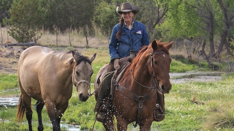 Missy Cantrell riding a horse and ponying another