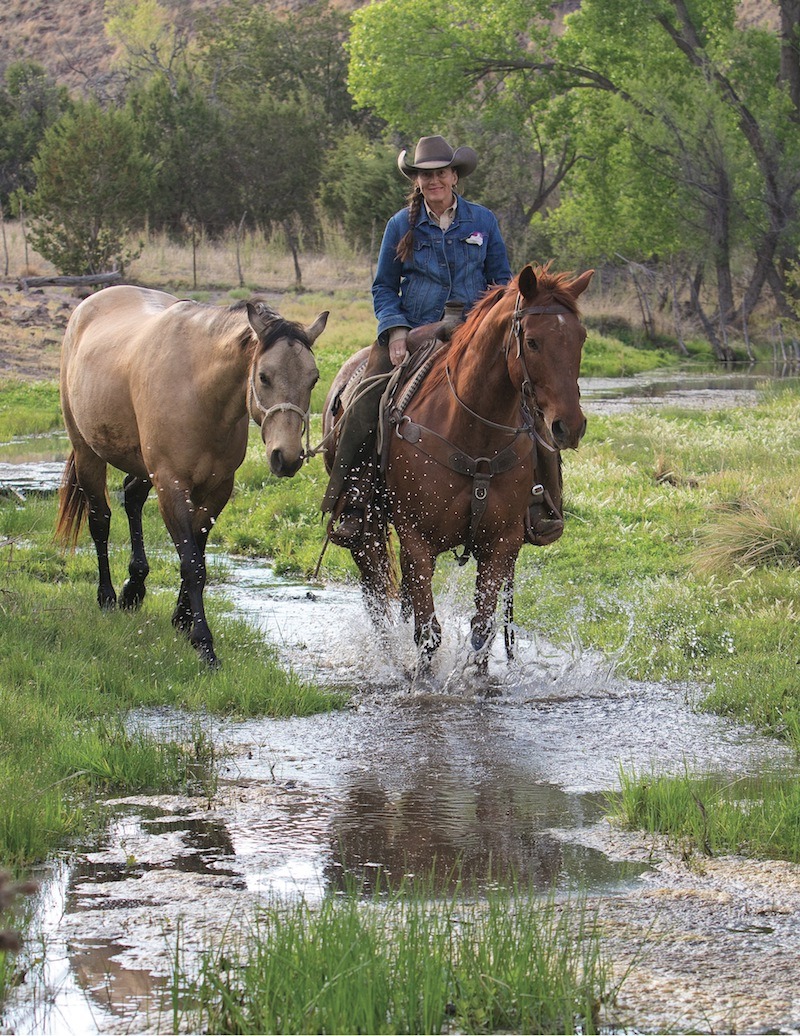 Missy Cantrell riding a horse and ponying another