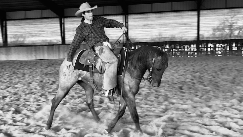 Luke Neubert riding a colt and touching it's hind end