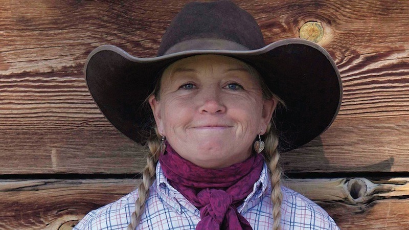 Sheila Carlson standing against a wood wall