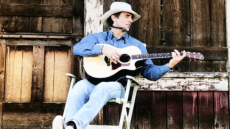 Gary Allegretto sitting in rocking chair with a guitar