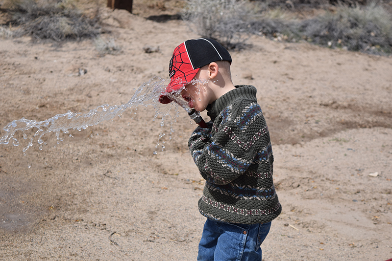 boy drinks water from garden hose