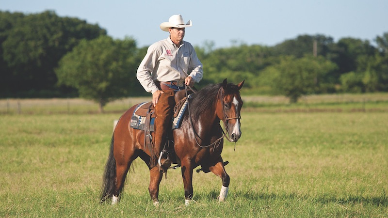 Kory Pounds riding horse through green pasture