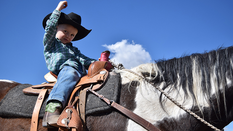 young cowboy rides horse