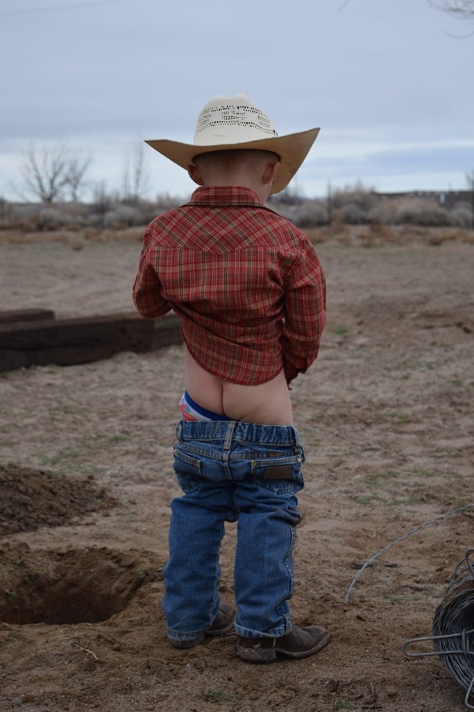 young cowboy goes to the bathroom outside