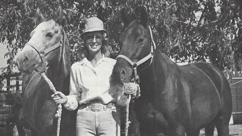 Edie Roer standing with two horses