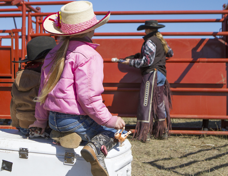 Eng kids sitting on a cooler watching their mom work the chute