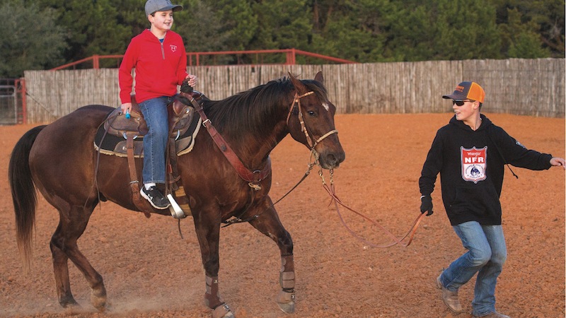 boys riding horse through arena