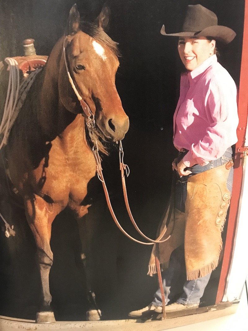 Kim Lindsey standing in barn doorway with horse