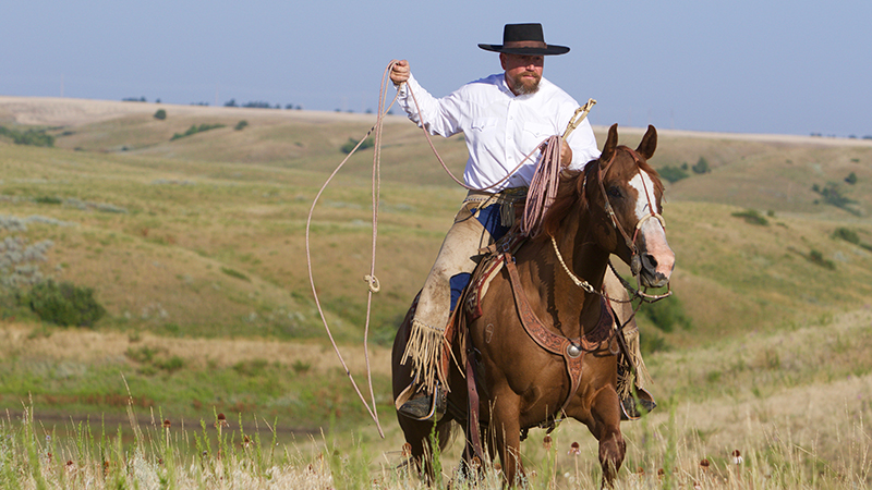 Scott Grosskopf swinging a ranch rope horseback