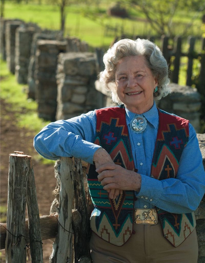 Trick Rider Mitzi Riley standing by fence