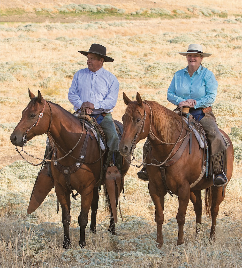 Buddy and Laurie Montes riding horses alongside each other