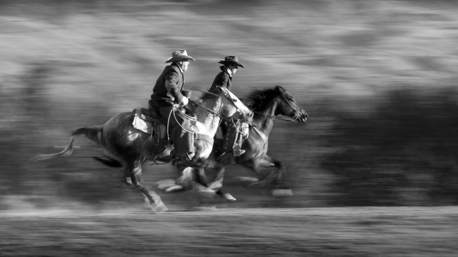Two riders gettin' it at a gallop.