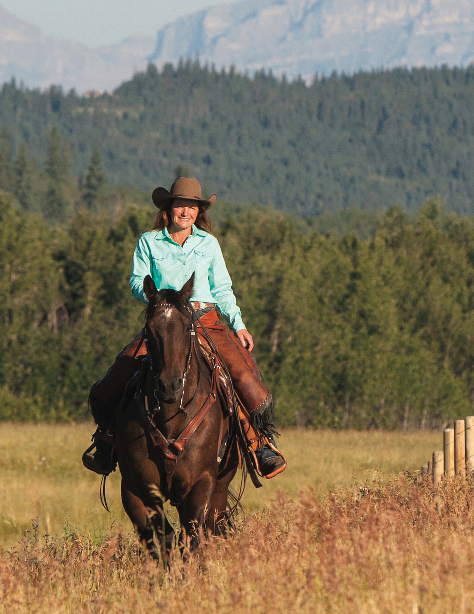 Mary Beth Sibbald riding horse through Alberta pasture