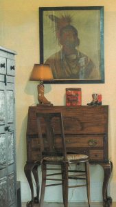 Western art hanging above an antique desk.