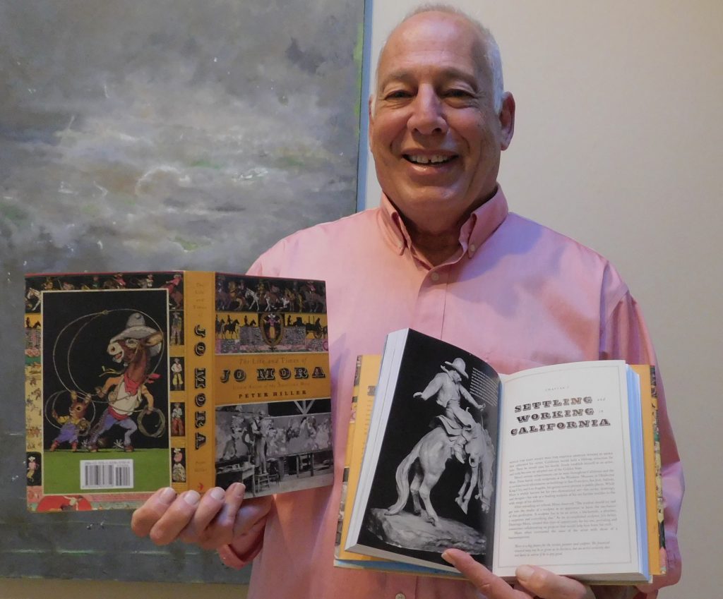 Peter Hiller stands with his newly written book.