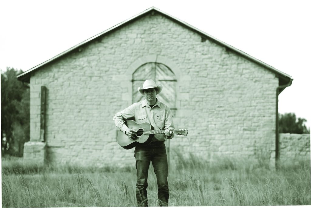 Andy Hedges standing holding a guitar