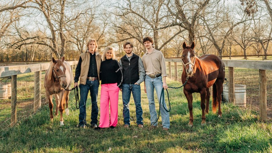 A family stands holding two horses.