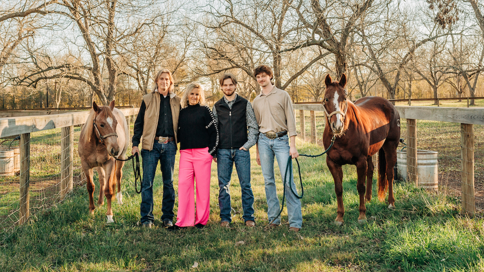 A family stands holding two horses.