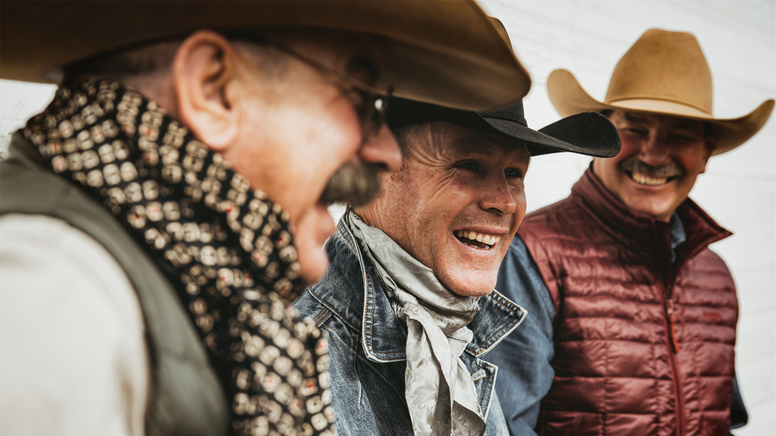 Three cowboys in their Resistol hats laughing.
