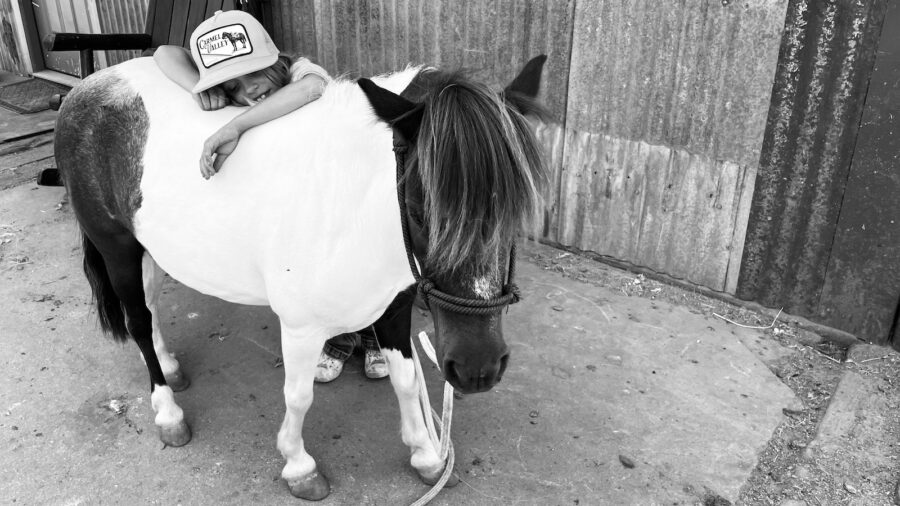 black and white image of a girl hugging a pony. Photography by Kelli Neubert
