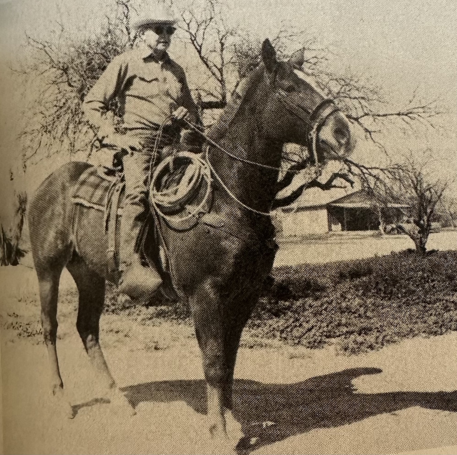 Black and white photo of Buzz Davies on a horse in the yard at X2