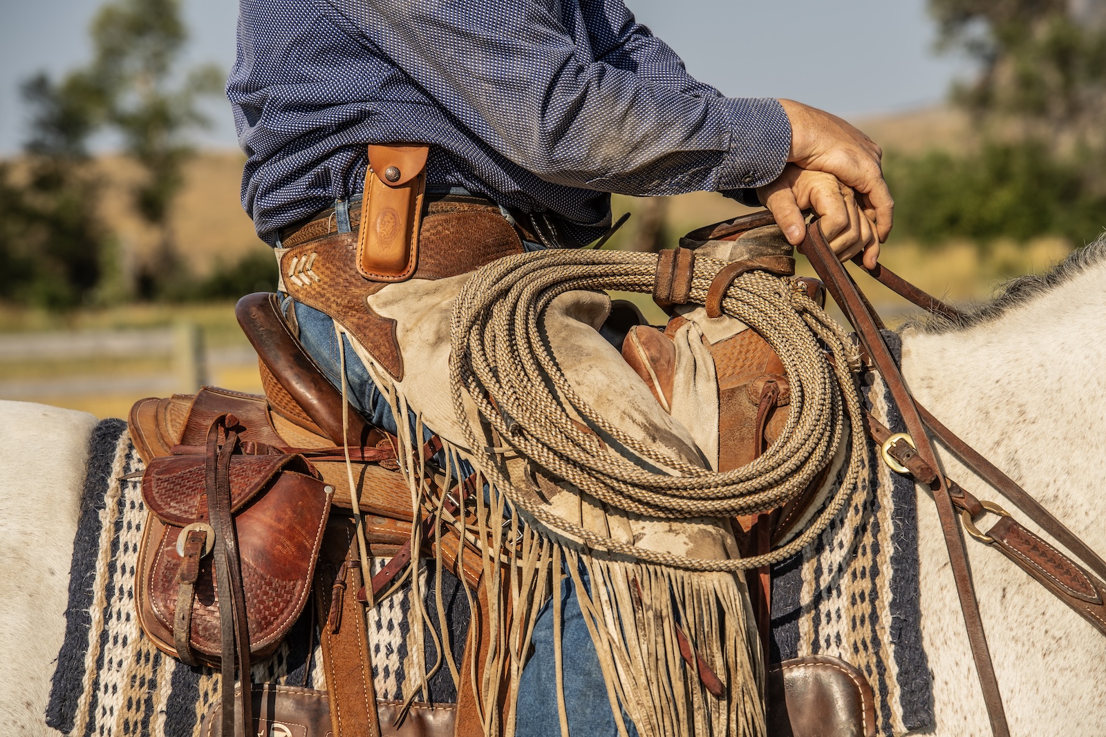 Cowboy sitting horseback showing his case knife securely in its case on his belt