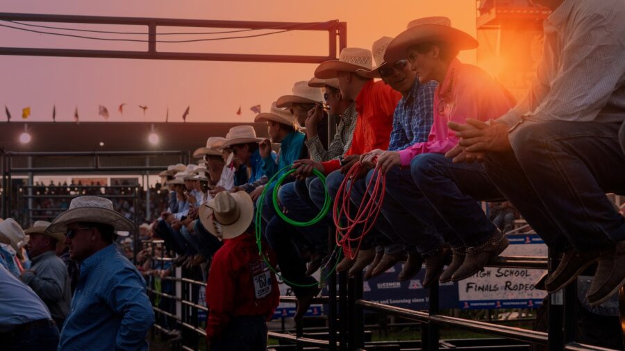 NHSFR competitors sit on the arena fence at sunset watching events